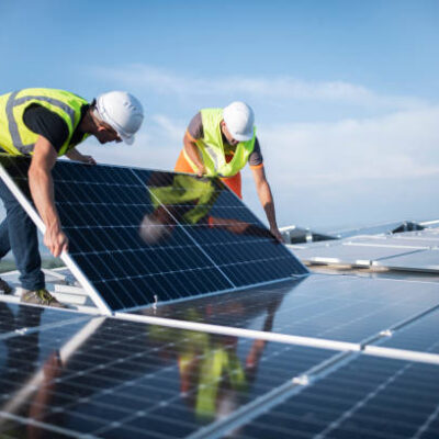 Team of two engineers installing solar panels on roof.